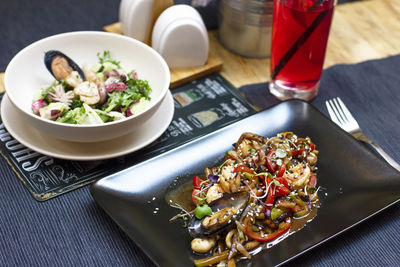 Salad with seafood mussels, octopus and vegetables in black plate on the table