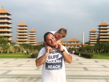 Man with son standing on footpath against sky