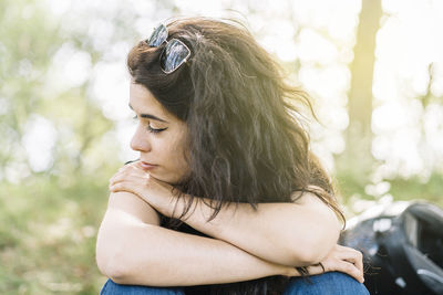 Pensive woman in nature sitting resting on her motorcycle route with her helmet behind