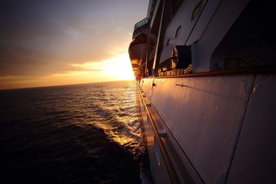 Cropped image of cruise ship in sea against at sunset