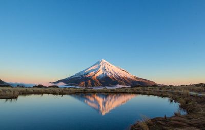 Scenic view of lake against clear blue sky during winter