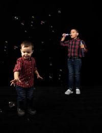 Full length of a boy standing against black background