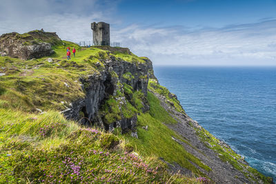 Tourists sightseeing moher tower on hags head, cliffs of moher, ireland