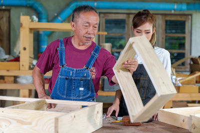 Tutor with female carpentry student in workshop studying for apprenticeship at college ,