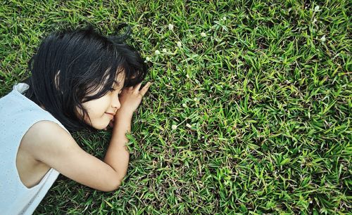 Side view of young woman laying down on grass