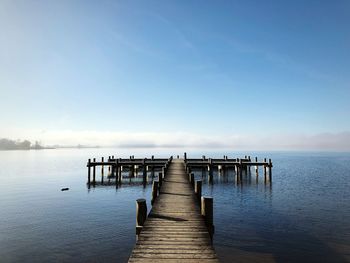 Pier over sea against clear blue sky