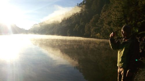 People looking at lake against sky