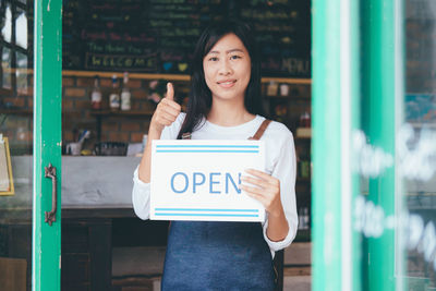 Portrait of a smiling woman standing at store