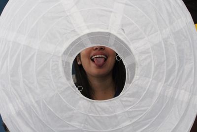 Woman sticking out tongue seen through white paper lantern