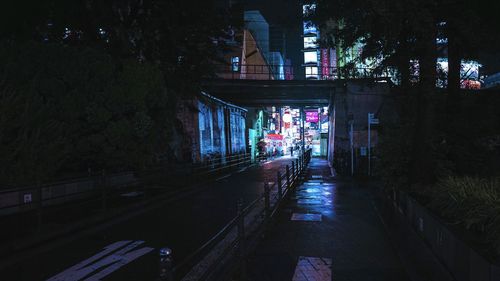 Illuminated footpath amidst buildings in city at night