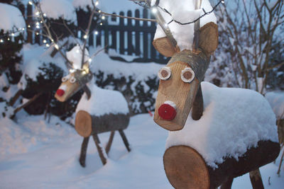 Wooden reindeer sculptures on snow covered field
