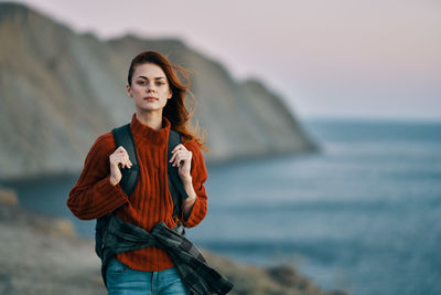 Portrait of young woman standing against sea