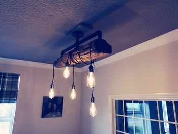 Low angle view of illuminated pendant lights hanging on ceiling