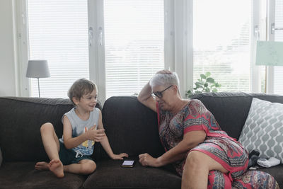 Rear view of women sitting on sofa at home