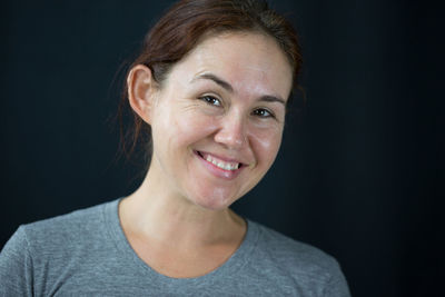 Close-up portrait of young woman against black background