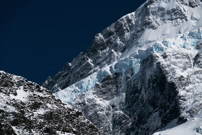 Low angle view of snowcapped mountain against clear sky