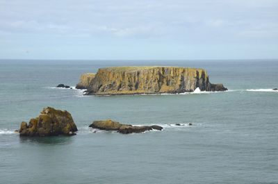 Rock formation in sea against sky