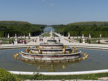 Fountain in park by lake against sky