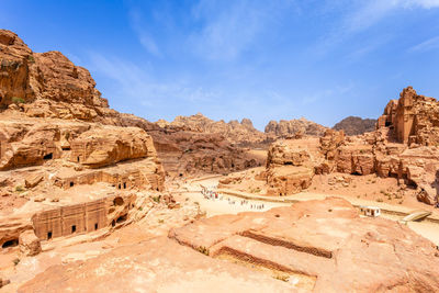 View to the ancient nabataean royal tombs and main street of petra full of tourist, jordan