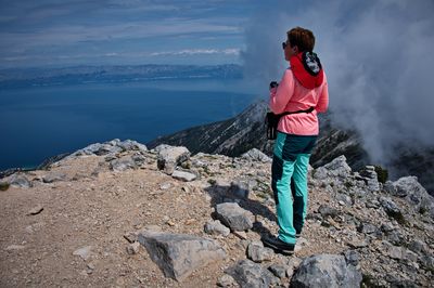 Rear view of woman standing on rock