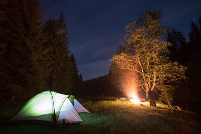 Illuminated tent on field against sky at night