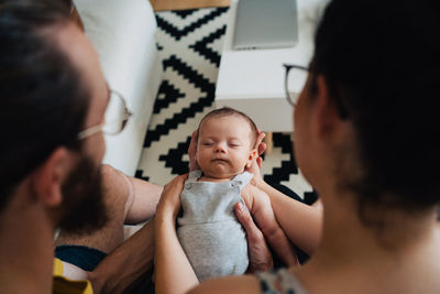 High angle view of young parents with their baby relaxing at home looking at new born