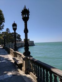 Street light by sea against clear blue sky