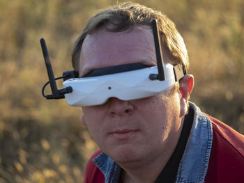 Close-up of man wearing virtual reality against sky during sunset