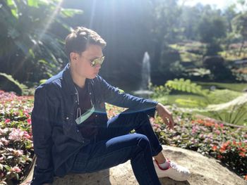 Young man looking away while sitting on land