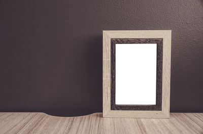 Close-up of blank picture frame against wall at home