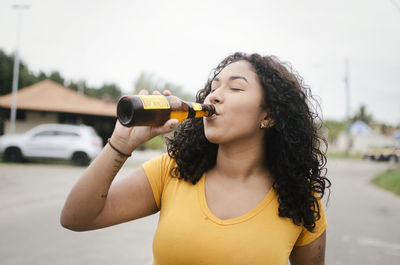 Young woman with curly hair drinking beer