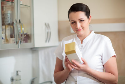 Portrait of smiling beautician holding product 