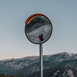 Low angle view of man reflecting in mirror outdoors