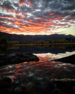 Scenic view of lake against dramatic sky during sunset