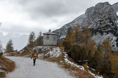 Female hiker wearing winter clothes, walking on path with amazing view in mountains