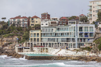 Buildings by sea against sky