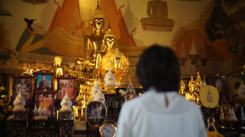 Woman standing in front of buddha statues in temple 