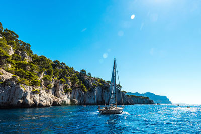 Sailboat sailing on sea against clear blue sky