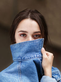 Girl with beautiful brown eyes covers her face with a denim collar