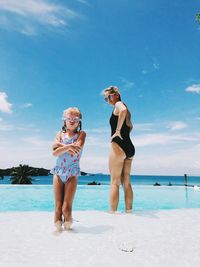 Full length of friends on beach against sky