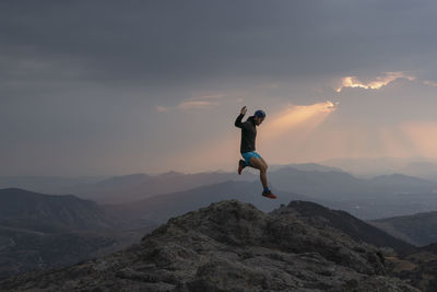 One man jumping between rocks while trail running at sunset