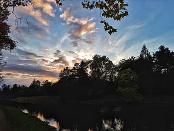 Silhouette trees by lake against sky during sunset