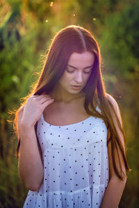 Portrait of young woman standing against plants