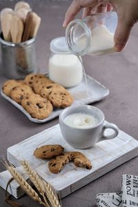 Milk and cookies splash milk hand in frame  high angle view of food on table