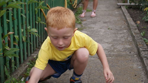 Boy crouching on footpath