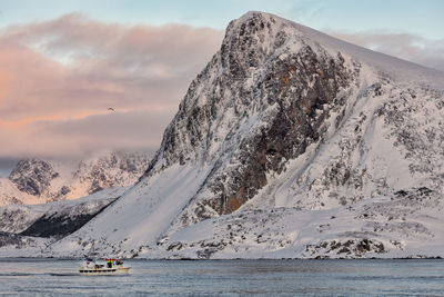 Scenic view of snowcapped mountains by sea against sky