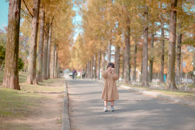 Full length of woman walking on footpath amidst trees