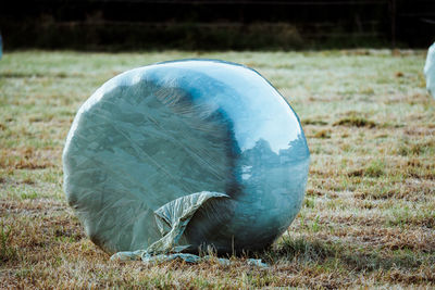 Close-up of wrapped hay bale on grassy field