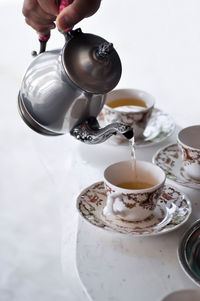 Midsection of person pouring tea in cup