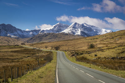 Road amidst snowcapped mountains against sky